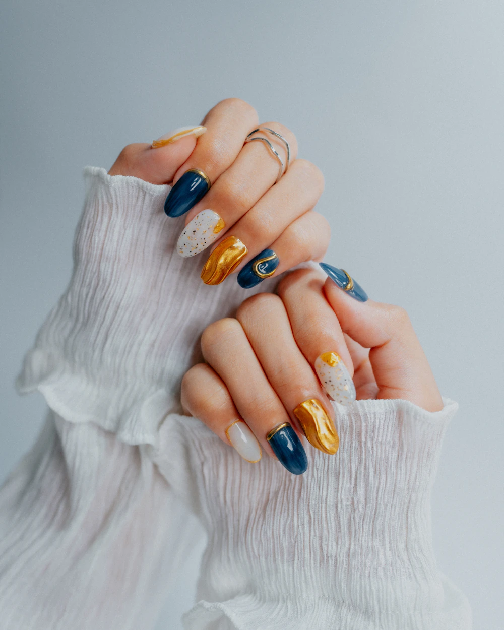 Almond nails in navy, gold and white with mixed designs